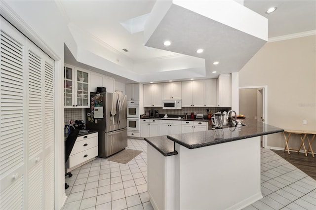 kitchen featuring backsplash, crown molding, light tile patterned flooring, white appliances, and a sink