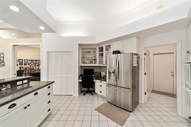 kitchen featuring ornamental molding, built in desk, white cabinetry, recessed lighting, and stainless steel fridge with ice dispenser