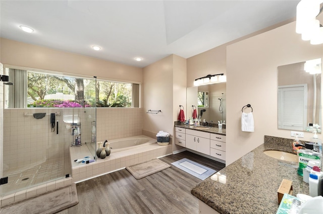 bathroom with a sink, wood finished floors, a garden tub, and a stall shower