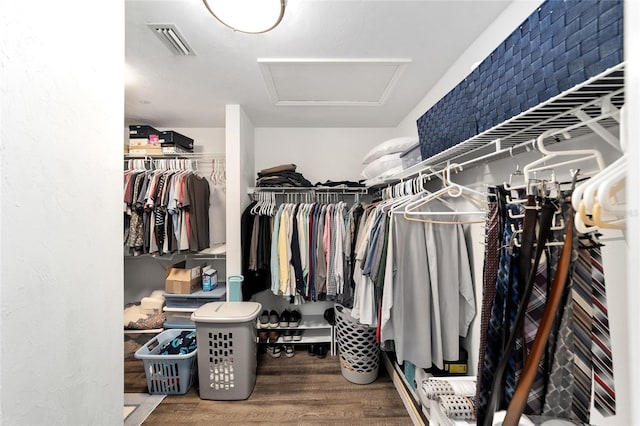 walk in closet with visible vents, attic access, and wood finished floors