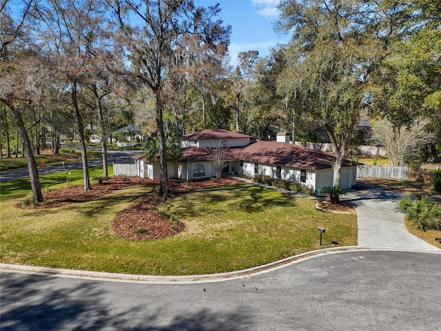 view of front facade featuring a garage, driveway, a front lawn, and fence