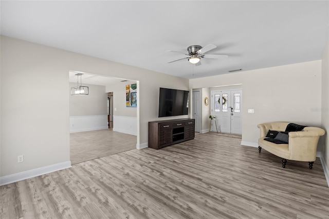 unfurnished living room featuring visible vents, baseboards, a ceiling fan, and wood finished floors