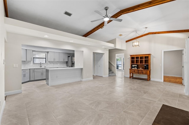 unfurnished living room featuring visible vents, baseboards, and a ceiling fan