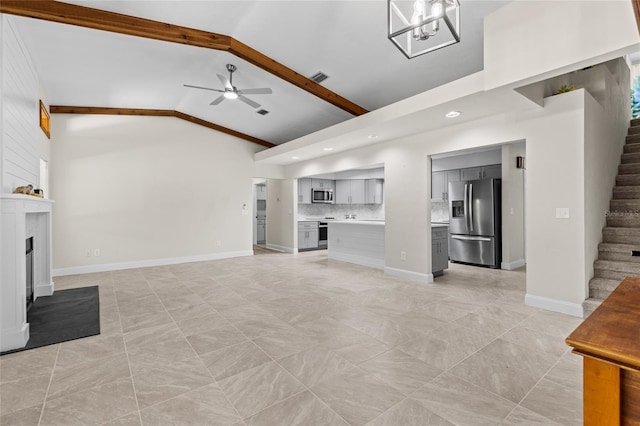 unfurnished living room with baseboards, stairway, beamed ceiling, ceiling fan with notable chandelier, and a fireplace