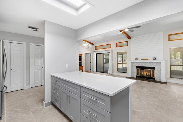 kitchen featuring visible vents, a fireplace with flush hearth, a ceiling fan, gray cabinets, and light countertops