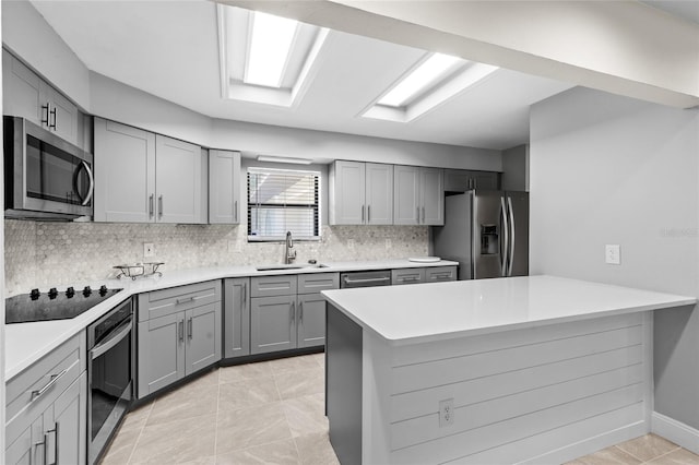 kitchen featuring gray cabinets, a sink, stainless steel appliances, light countertops, and decorative backsplash