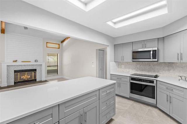 kitchen with decorative backsplash, appliances with stainless steel finishes, and gray cabinets