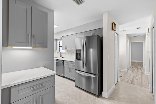 kitchen with visible vents, light countertops, gray cabinets, stainless steel appliances, and a sink