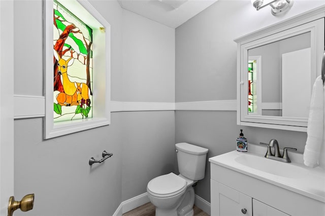 bathroom featuring toilet, vanity, baseboards, and wood finished floors