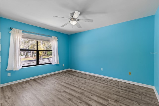 spare room with baseboards, wood finished floors, and a ceiling fan