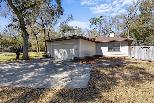 view of front of property featuring an attached garage, fence, driveway, and a chimney