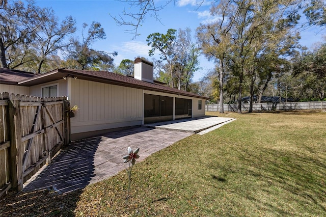 rear view of property featuring a lawn, a chimney, a patio, and fence