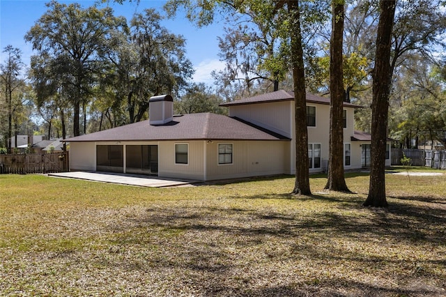 rear view of property with a patio, a lawn, a chimney, and fence