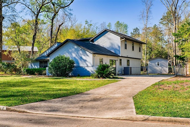 view of front of house featuring concrete driveway, central air condition unit, fence, and a front yard