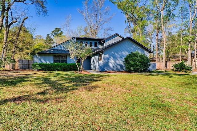 mid-century home featuring a front lawn and fence