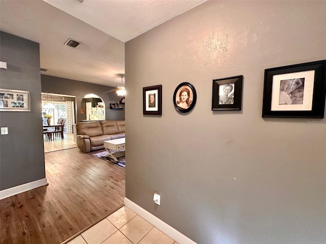 corridor featuring arched walkways, visible vents, baseboards, and wood finished floors