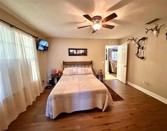 bedroom featuring a ceiling fan, dark wood-style floors, visible vents, and baseboards