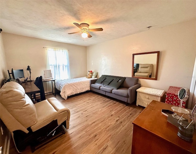 bedroom with ceiling fan, a textured ceiling, and wood finished floors