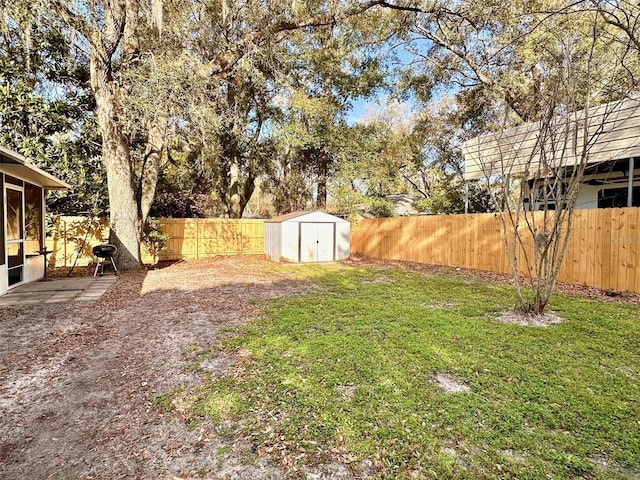 view of yard featuring an outbuilding, a fenced backyard, and a shed