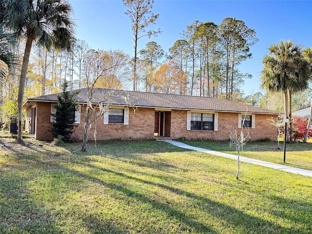 ranch-style house featuring cooling unit, brick siding, and a front lawn