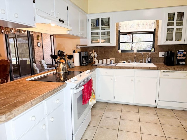 kitchen with decorative backsplash, light tile patterned flooring, white cabinets, white appliances, and a sink