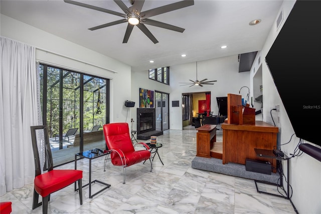 living area featuring visible vents, recessed lighting, a glass covered fireplace, marble finish floor, and a ceiling fan