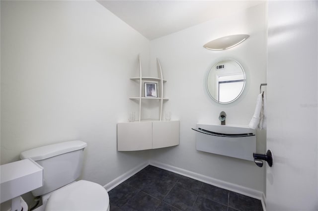 half bath with baseboards, toilet, and tile patterned flooring