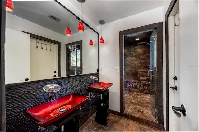 bathroom with a shower stall, stone finish floor, and visible vents