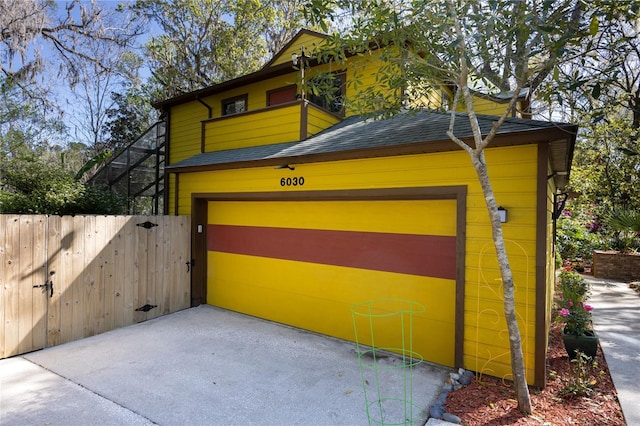 garage with a gate, driveway, and fence