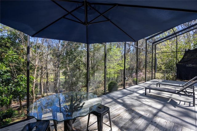 wooden deck with glass enclosure and a forest view