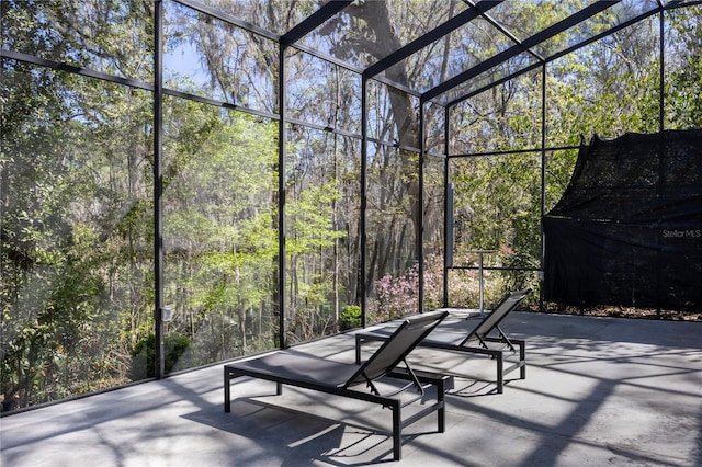 view of patio / terrace with a lanai and a view of trees