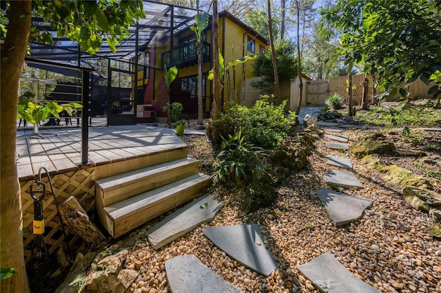 deck featuring glass enclosure, a patio, fence, and a gate