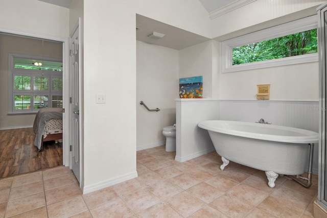 1132 SW 105th Ter, Gainesville, FL 32607 - ensuite bathroom featuring toilet, a freestanding bath, tile patterned flooring, lofted ceiling, and wainscoting