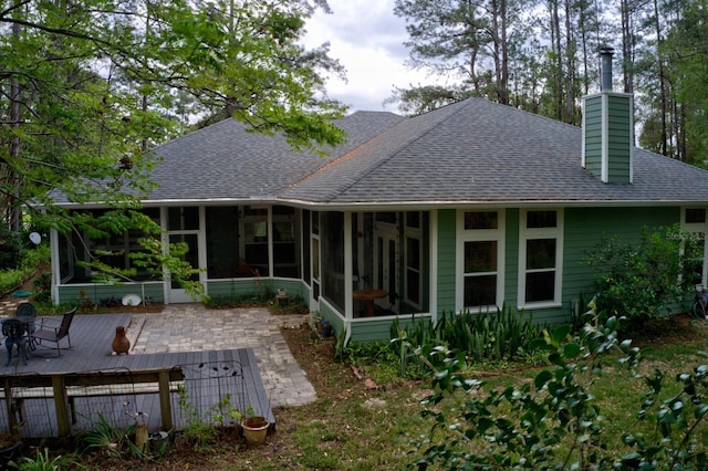 1132 SW 105th Ter, Gainesville, FL 32607 - rear view of house with a sunroom, a shingled roof, a chimney, and a patio area
