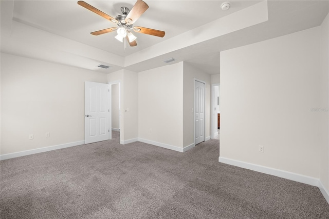 unfurnished room featuring visible vents, ceiling fan, baseboards, carpet, and a tray ceiling