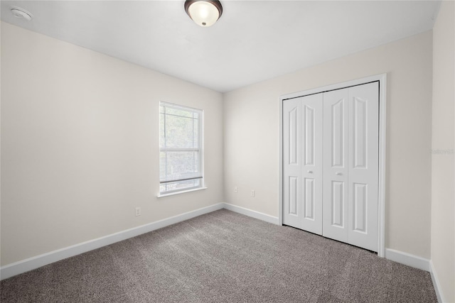 unfurnished bedroom with baseboards, carpet floors, and a closet