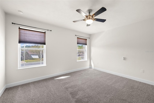 carpeted spare room featuring baseboards and ceiling fan