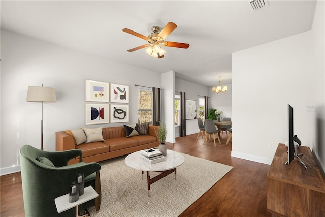 living area featuring dark wood finished floors, ceiling fan with notable chandelier, visible vents, and baseboards