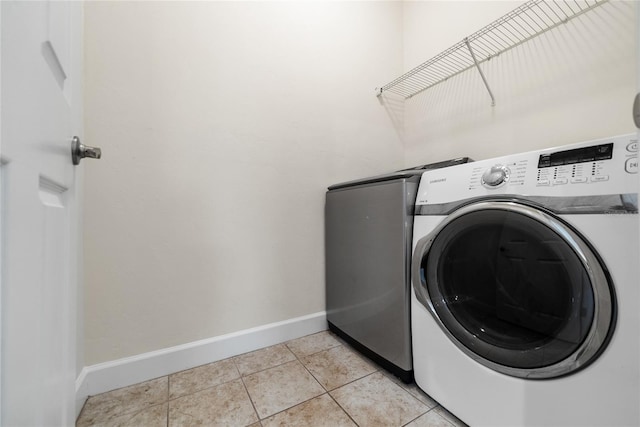 laundry room with light tile patterned flooring, laundry area, washer and clothes dryer, and baseboards