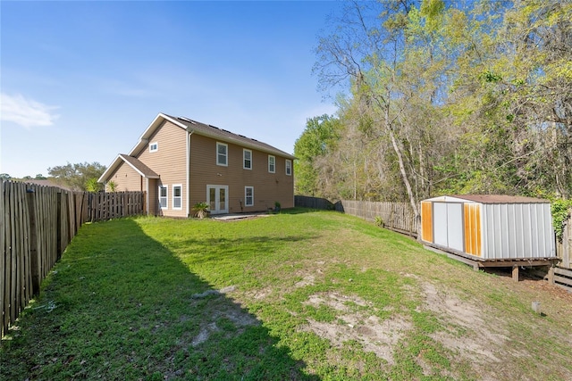 view of yard with french doors, an outbuilding, a storage shed, and a fenced backyard