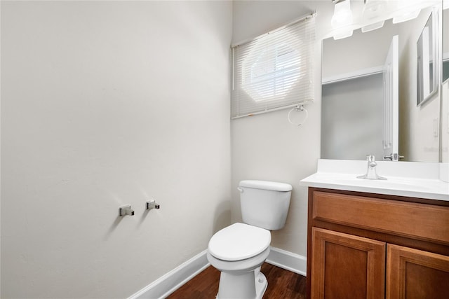 bathroom featuring toilet, vanity, baseboards, and wood finished floors