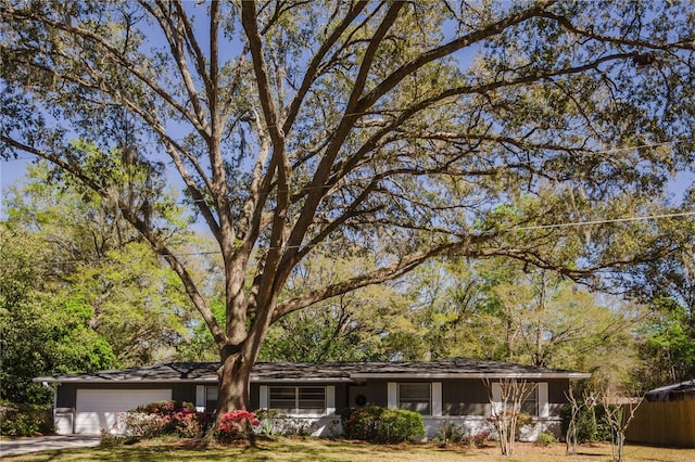 ranch-style house featuring driveway, an attached garage, and fence