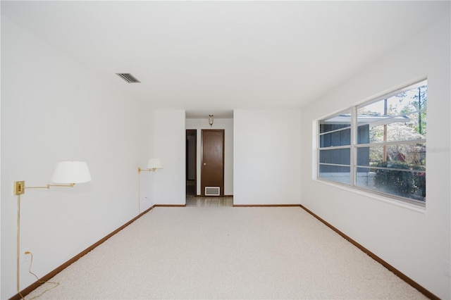 empty room featuring visible vents, baseboards, and light colored carpet