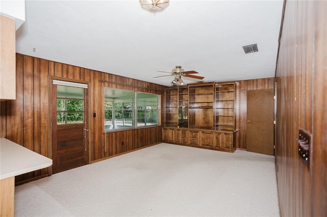 interior space featuring a ceiling fan, visible vents, and wood walls