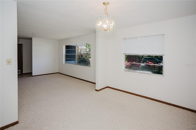 empty room featuring carpet flooring, a notable chandelier, and baseboards