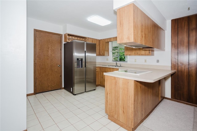 kitchen with a sink, a peninsula, stainless steel fridge with ice dispenser, light countertops, and white electric stovetop