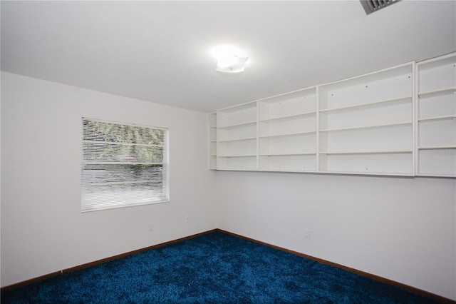 empty room with visible vents, dark carpet, and baseboards