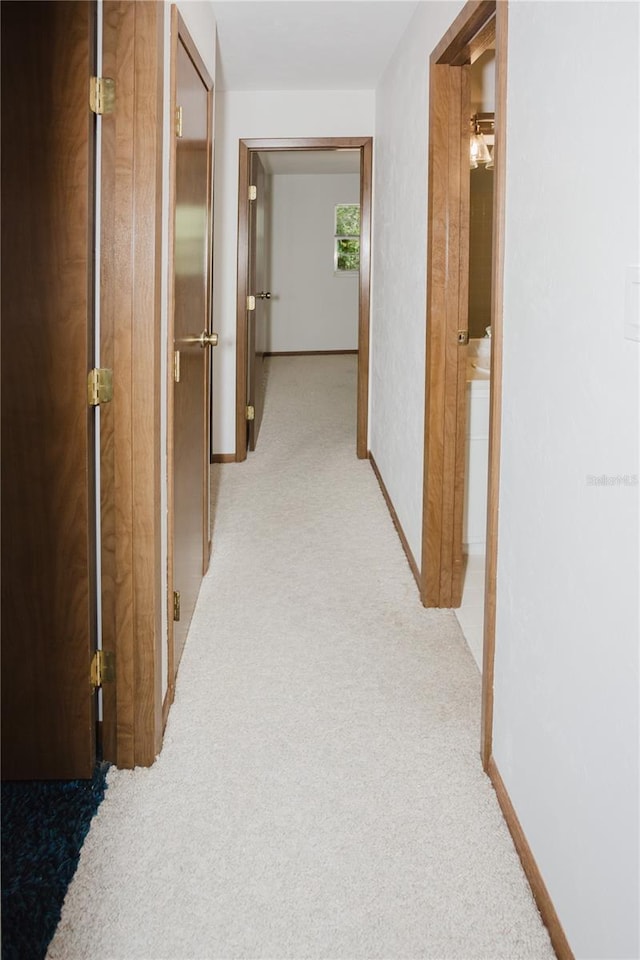 hall featuring light carpet and baseboards