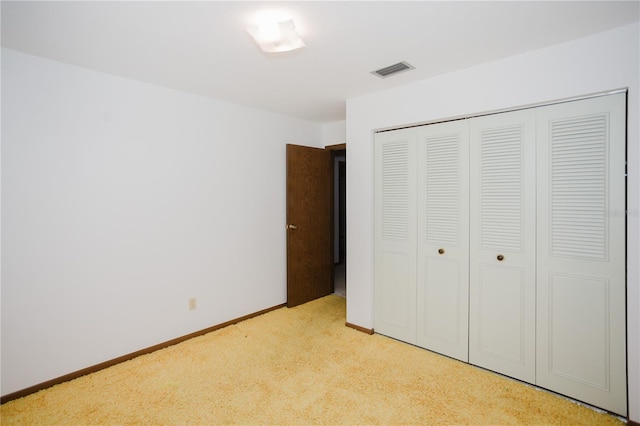 unfurnished bedroom with visible vents, baseboards, a closet, and light carpet