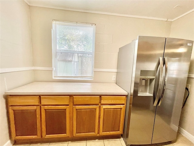 kitchen with brown cabinets, crown molding, stainless steel fridge with ice dispenser, and light countertops